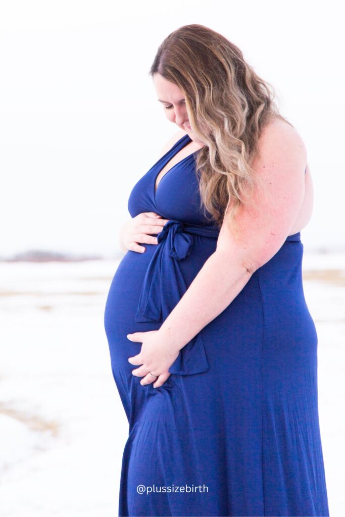 plus size pregnant woman with a b belly wearing a blue maternity dress 