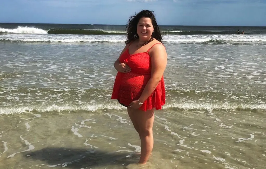 plus size maternity swim suit in red with smiling plus size pregnant woman