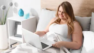 plus size woman on laptop in bed