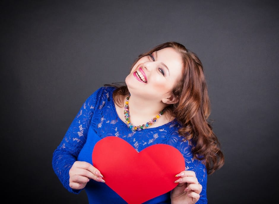 happy plus size woman holding a red heart 