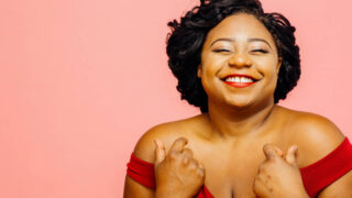plus size woman smiling and wearing a red dress
