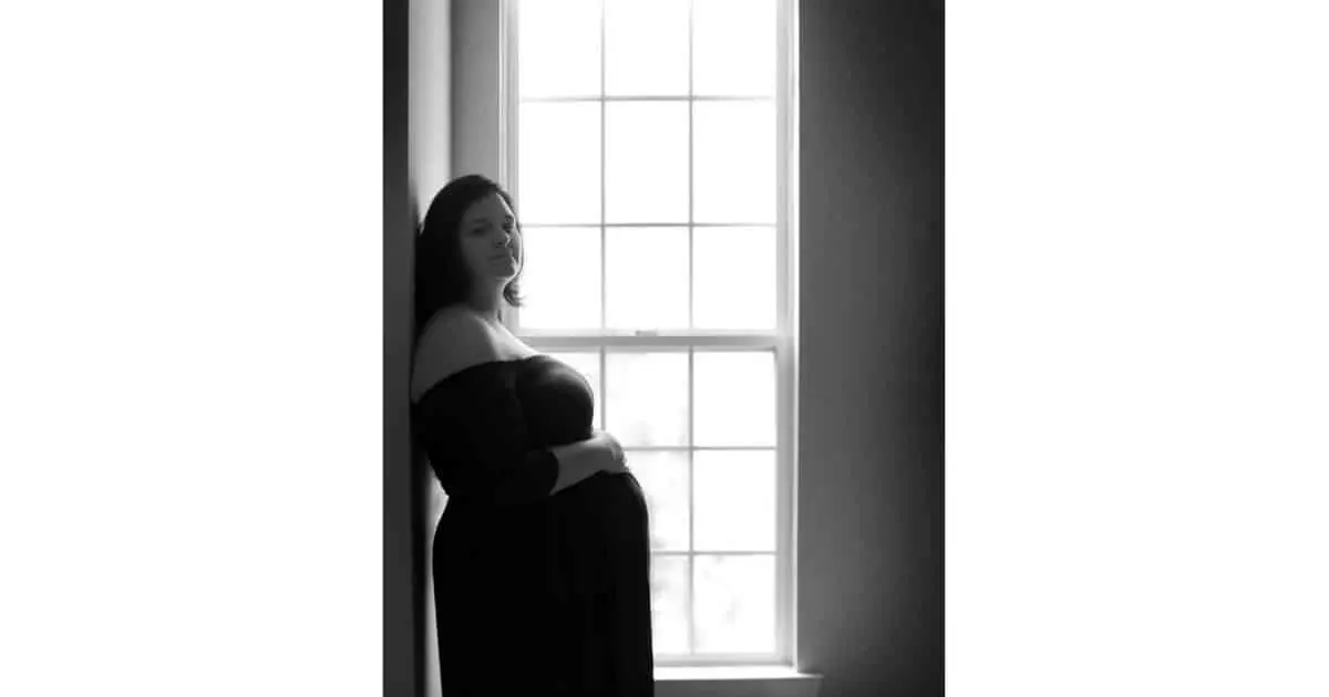 plus size pregnant woman wearing a long dress holding her belly 