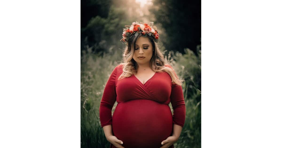 plus size pregnant woman wearing a red dress with a floral crown 