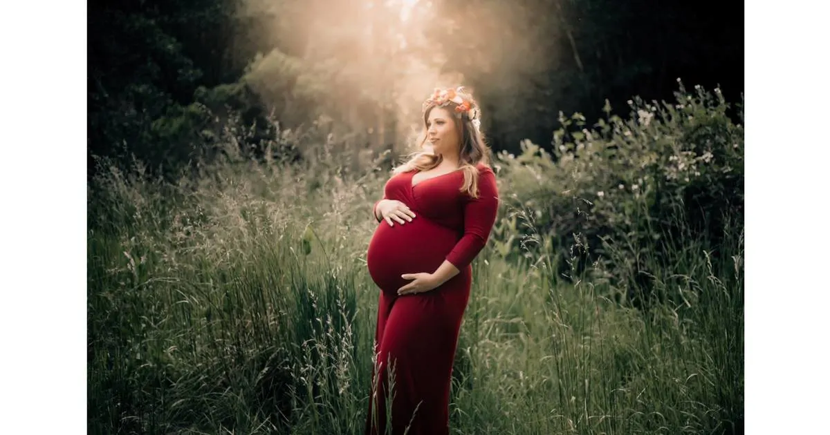 plus size pregnant woman in red dress with a floral grown standing in a crowd