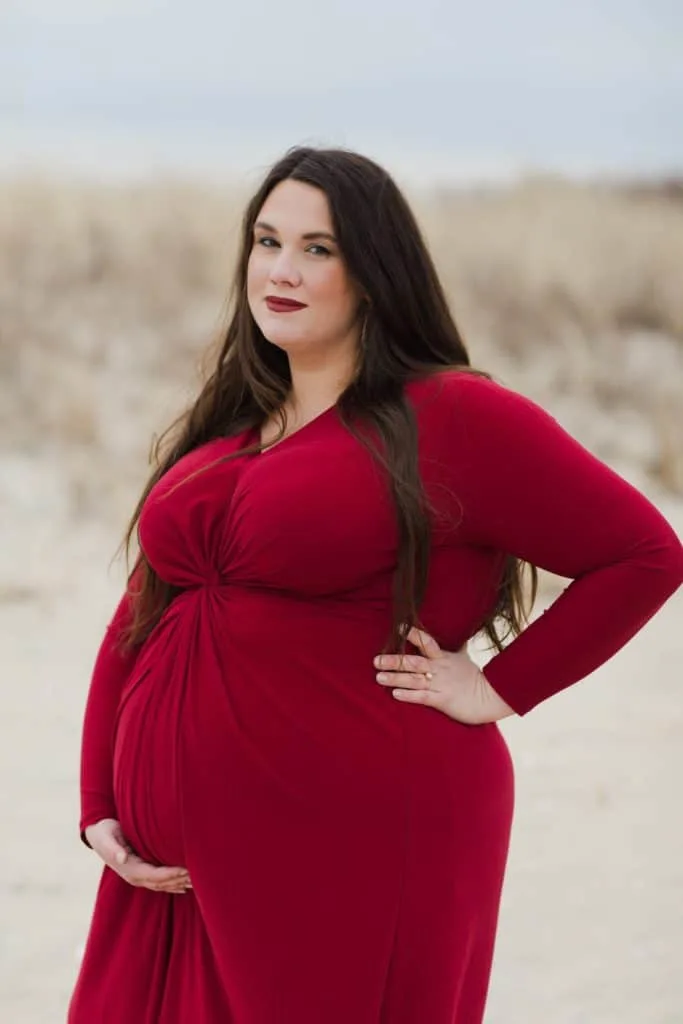 Plus size maternity photo of plus size woman wearing red maternity dress. 