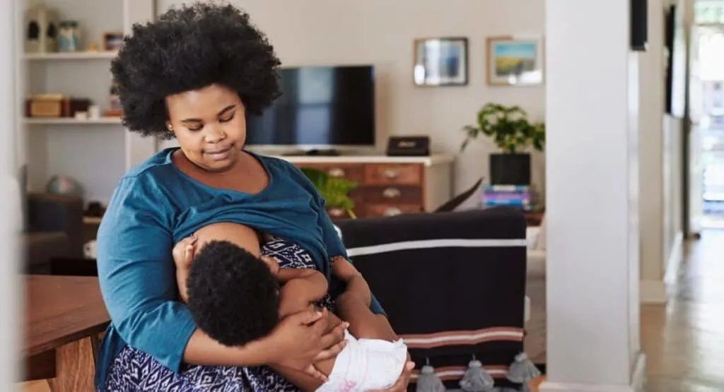 plus size breastfeeding mom holding her newborn while nursing standing up