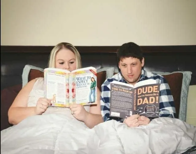 plus size couple in bed reading pregnancy books