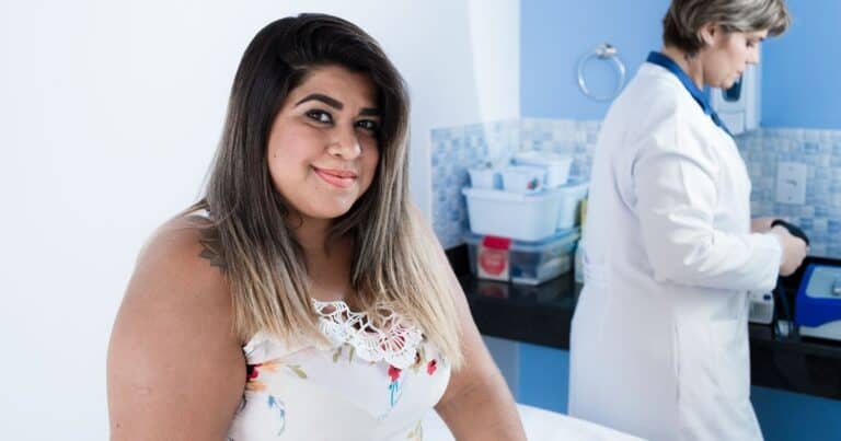 plus size pregnant woman on exam table with OBGYN in the background