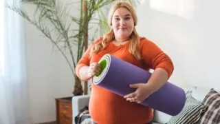 plus size woman holding yoga mat doing Pregnancy Exercises at Home