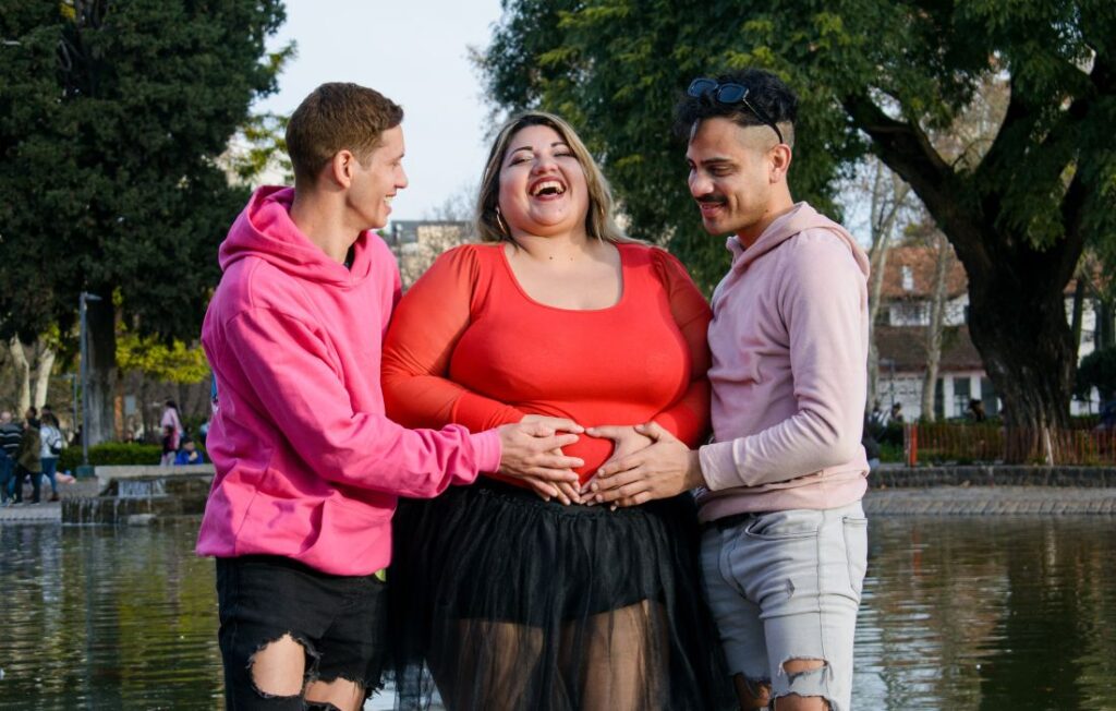 plus size pregnant woman with friends hands on belly