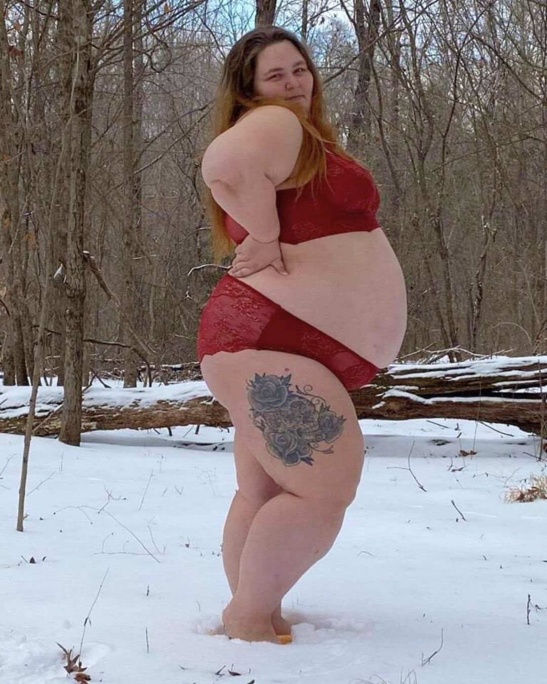 plus size pregnant woman doing a boudoir-inspired plus size maternity photo shoot in red lingerie.