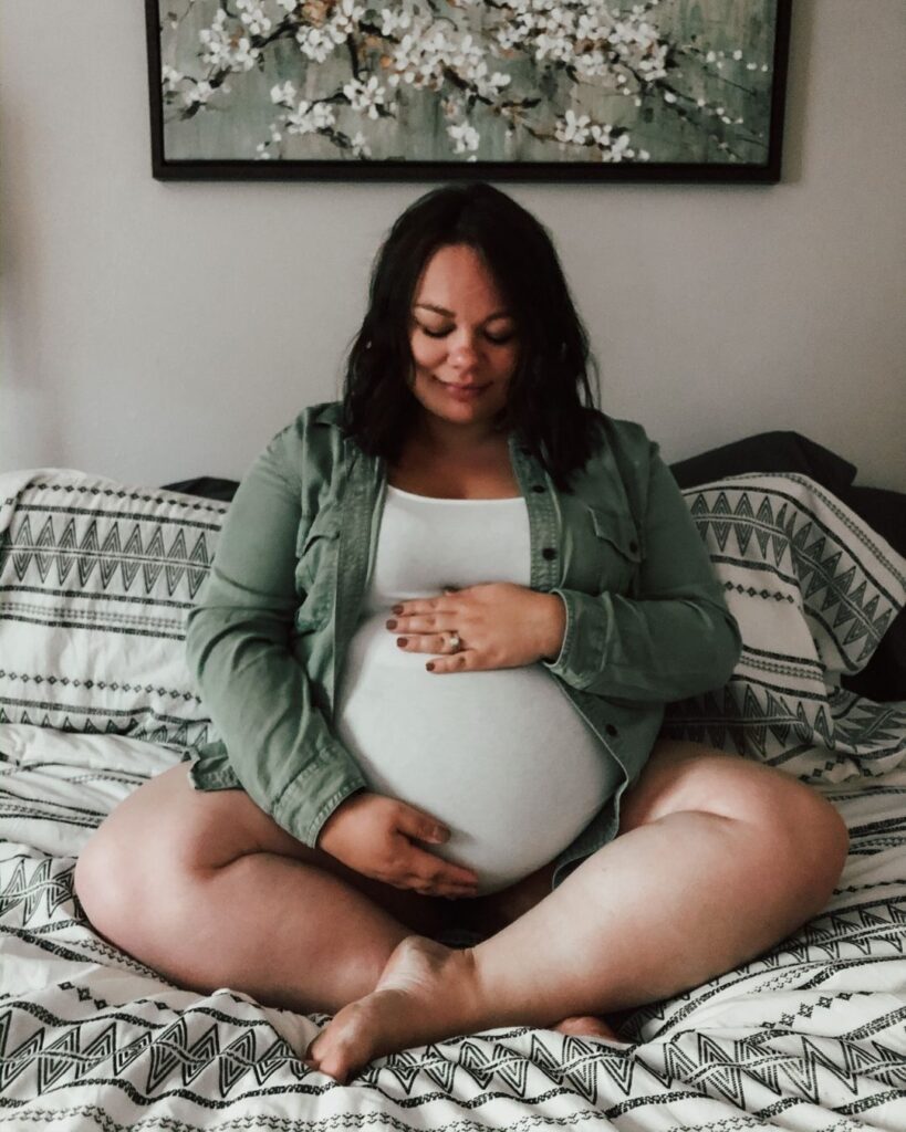 Woman risscrossed on the Bed maternity Pose plus size