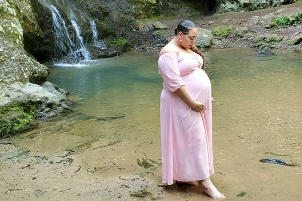 plus size pregnant woman with twins wearing a pink maternity dress