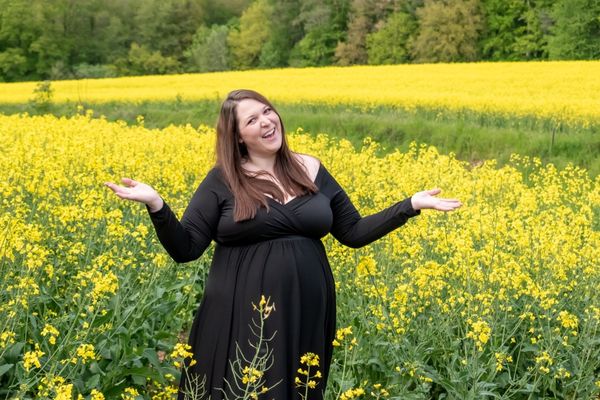fun plus size maternity photo in a field of yellow flowers
