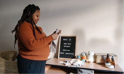 plus size pregnant woman holding baby clothes